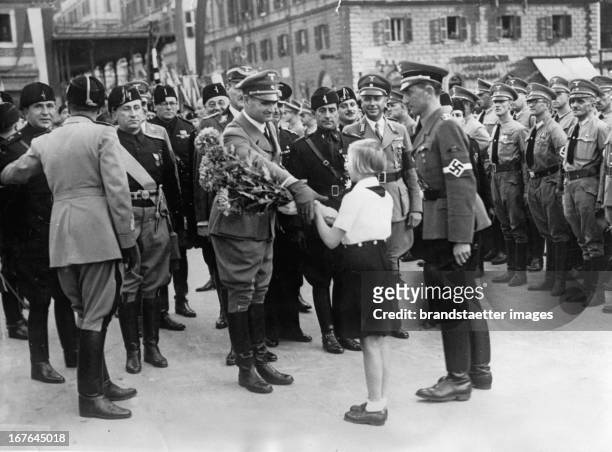 Girl handes a bouquet to Rudolf Heß at his arrival in Roma. In front of the train station. October 28th 1937. Photograph. Ein BDM-Mädchen überreicht...
