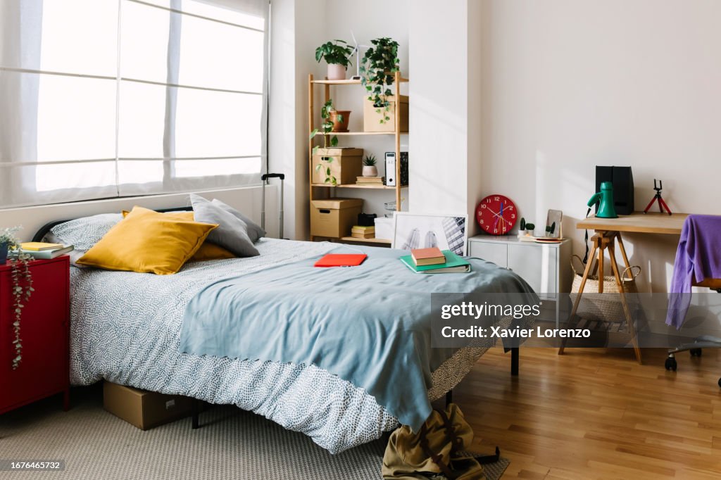 Interior of messy teenage bedroom with bed and workplace.
