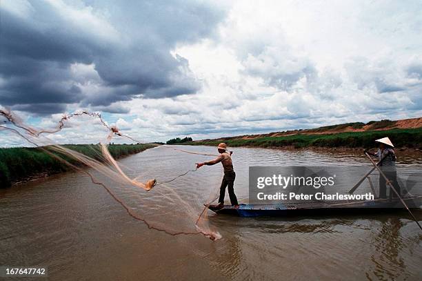 Man throws his fishing net into a canal while fishing illegally in the bird sanctuary called Tram Chim near the Vietnamese border with Cambodia..