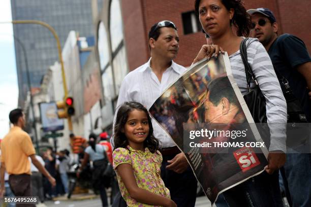 Venezuelan mother holds a poster with the photograph of her daughter hugging Venezuelan President Hugo Chavez during a demonstration pro a new...