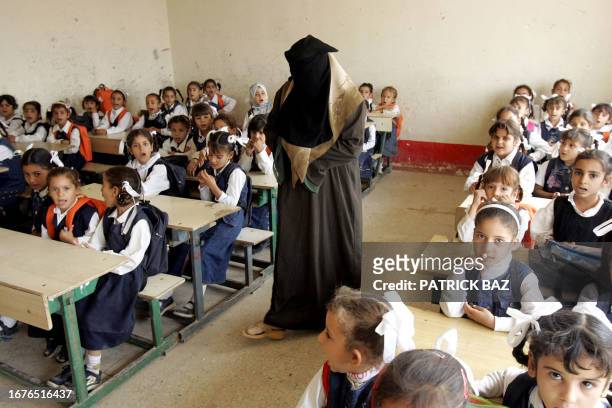 Veiled Iraqi teacher makes her class recites verses of the Koran in a ruined school in the southern part of Fallujah 18 October 2005. More than 60...