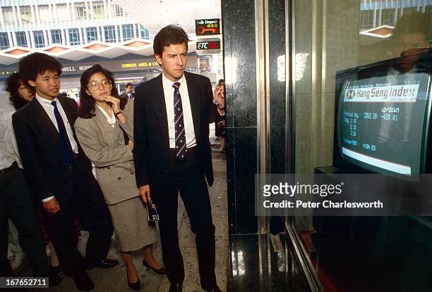 Black Monday. Business people watch a TV monitor in a bank window in Central, Hong Kong showing the falling Heng Seng index during the economic crash...
