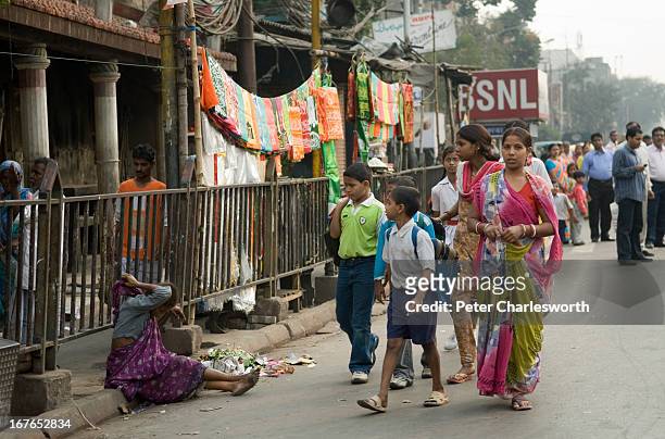 Family walks past a beggar on a Kolkata street..