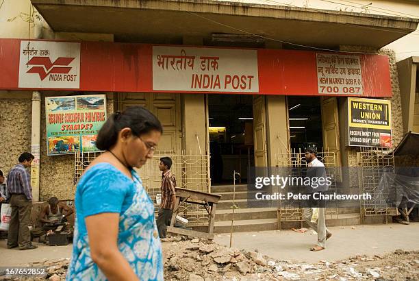 Woman walks past a pile of rubble outside of a Post Office in a small Kolkata street..