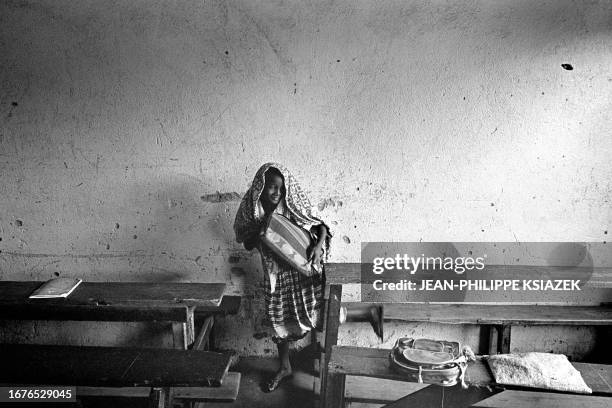 An Ivorian girl takes her books 22 March 2001 in a Koranic school in a low-income neighborhood of Abidjan. Muslim children in Abidjan's poor...