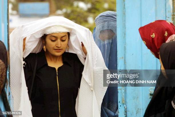 Schoolgirl takes off her burka while walking through the gate of a girls school in Mazar I Sharif as Afghanistan opens 23 March 2002 a new school...