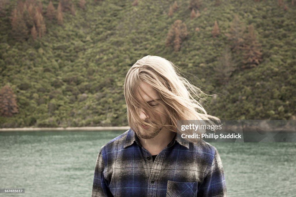 Man with long hair looking down into ocean