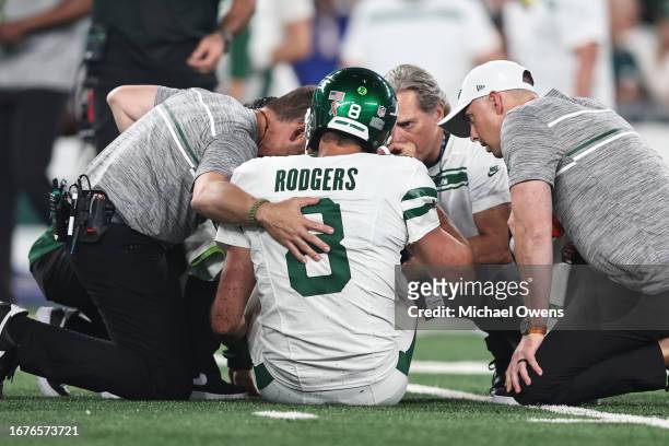 Aaron Rodgers of the New York Jets is looked at by the medical staff on the field for an apparent injury during a game against the Buffalo Bills at...
