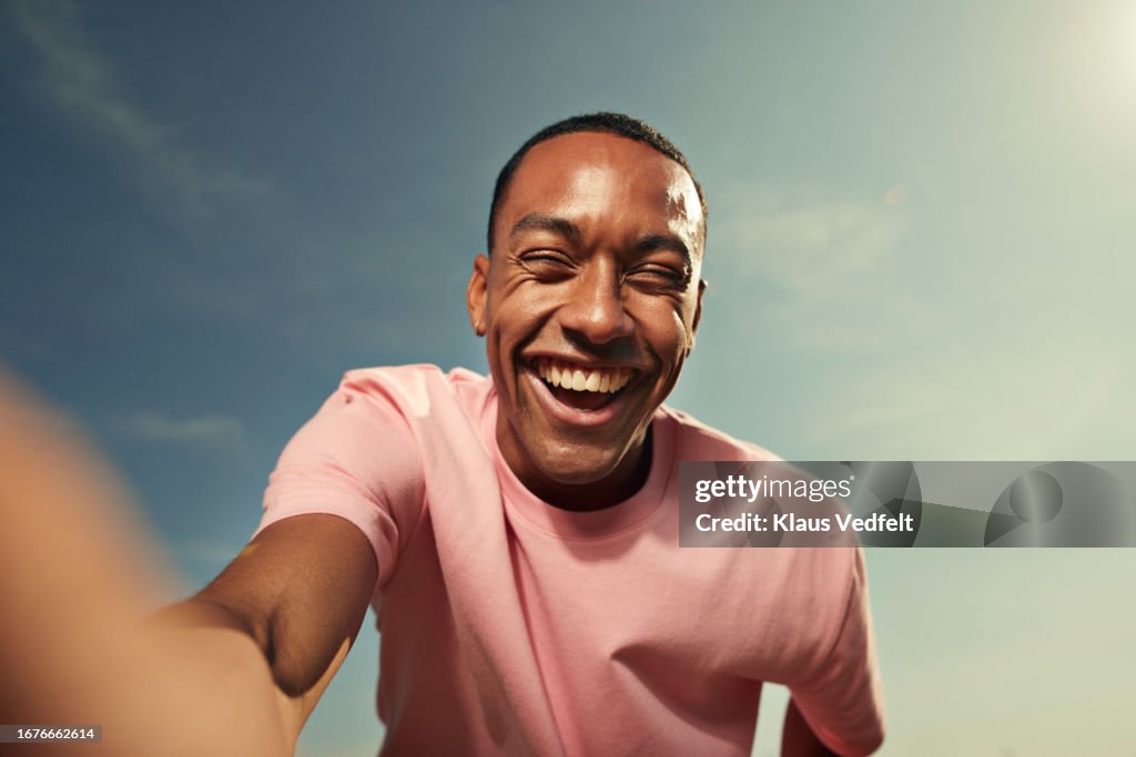 Cheerful woman laughing against sky
