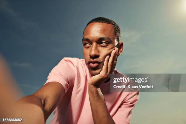 young man with hand on chin against sky - duck face selfie stock pictures, royalty-free photos & images