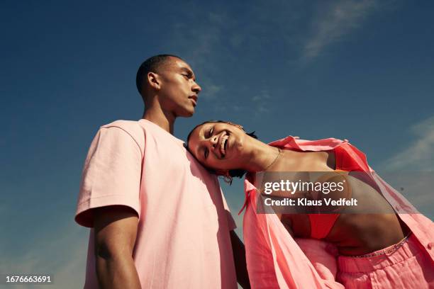 smiling woman leaning on man against sky - fashion couple stock-fotos und bilder