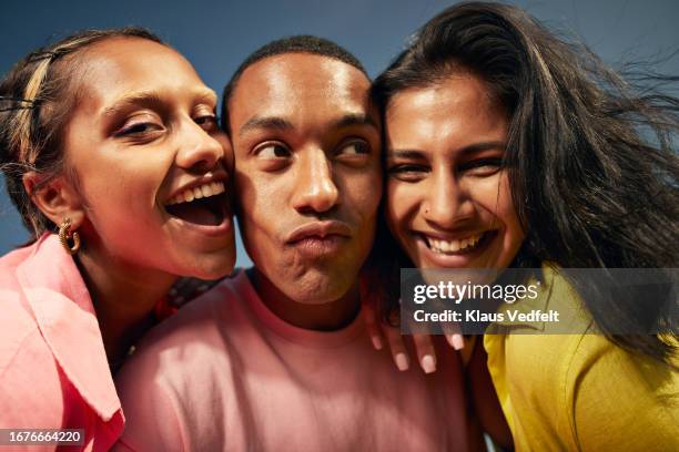 cheerful friends with cheek to cheek against sky - homme en contre plongée fait le pitre photos et images de collection