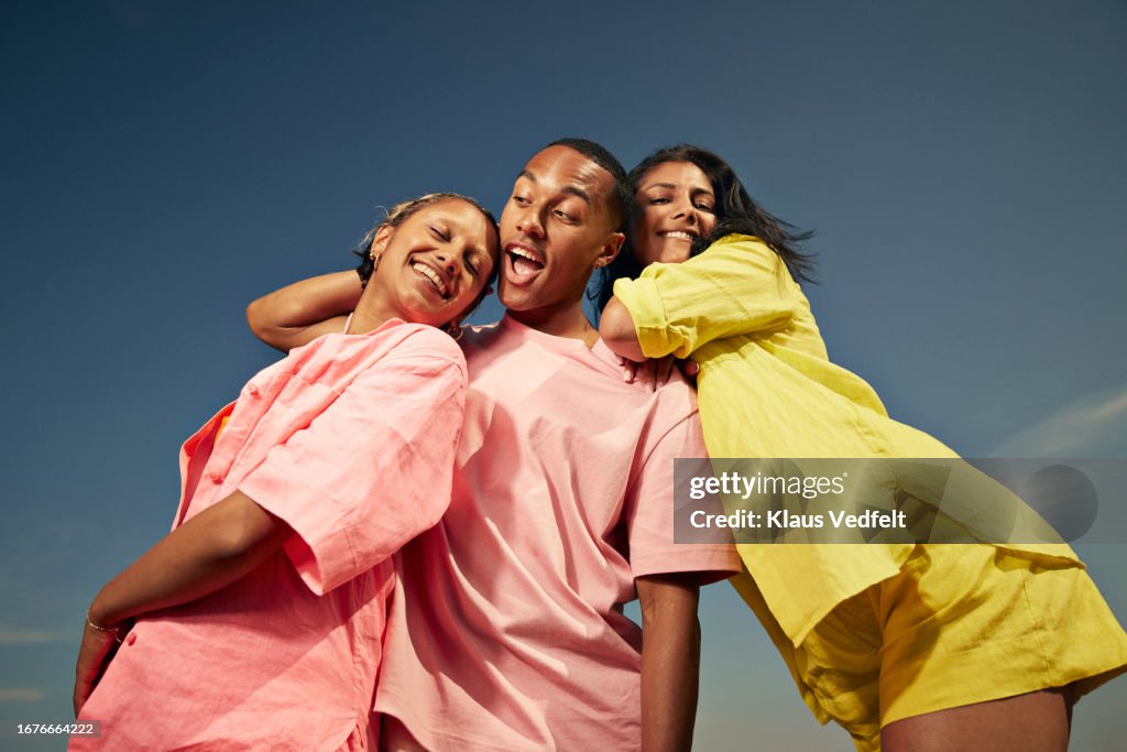 Carefree friends standing against sky