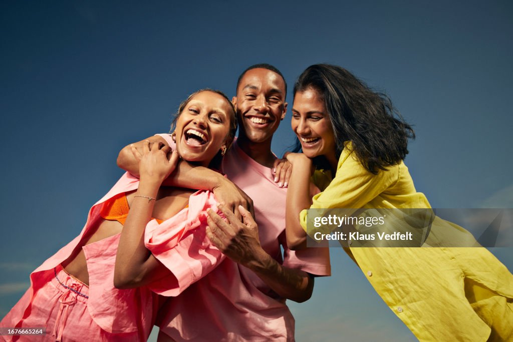 Cheerful friends laughing against sky