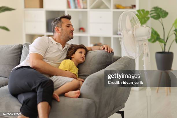 father children is front of electric fan on hot summer day - summer indoors stock pictures, royalty-free photos & images