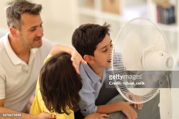 father children is front of electric fan on hot summer day - air conditioner family stock pictures, royalty-free photos & images
