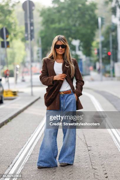 Gitta Banko, wearing a white top by Gitta Banko, a brown leather jacket by Gitta banko, a jeans with wide legs by Khaite, a brown bag by Khaite, a...