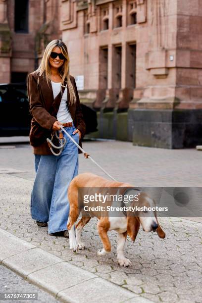 Gitta Banko, wearing a white top by Gitta Banko, a brown leather jacket by Gitta banko, a jeans with wide legs by Khaite, a brown bag by Khaite, a...