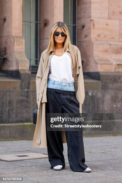 Gitta Banko, wearing a white shirt by gitta Banko, a beige coat by Herno, blue pants with jeans waist by Dion Lee, white sneakers Samba by Adidas, a...