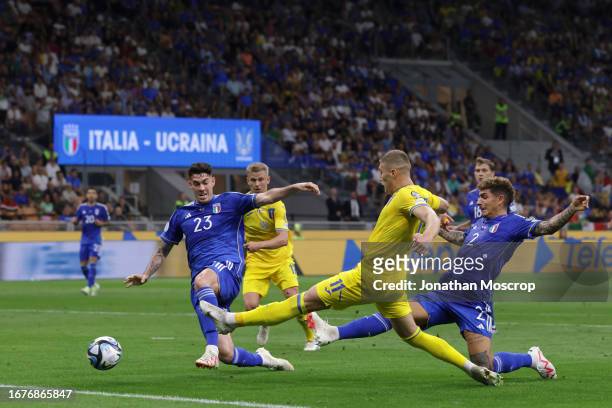Alessandro Bastoni and Giovanni Di Lorenzo of Italy stretch in an attempt to block Artem Dovbyk of Ukraine's shot in the lead up to Andriy...