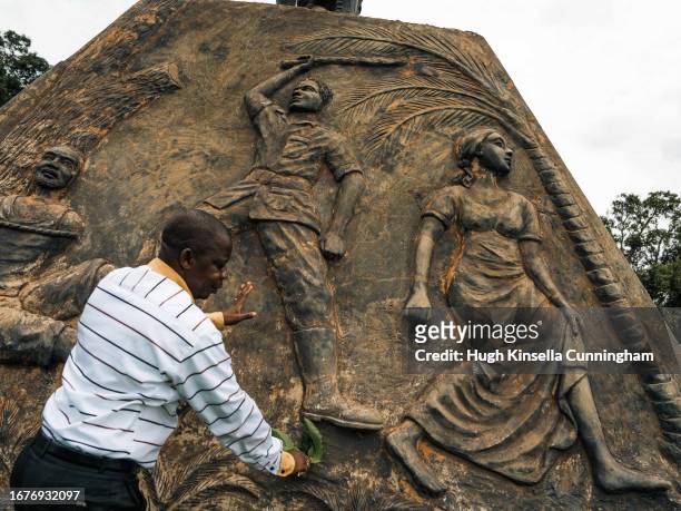 Priest Jean-Pierre Bagudekia, the coordinator of the DUNGU Commission for Justice and Peace, cleans a memorial to victims of the Lord's Resistance...