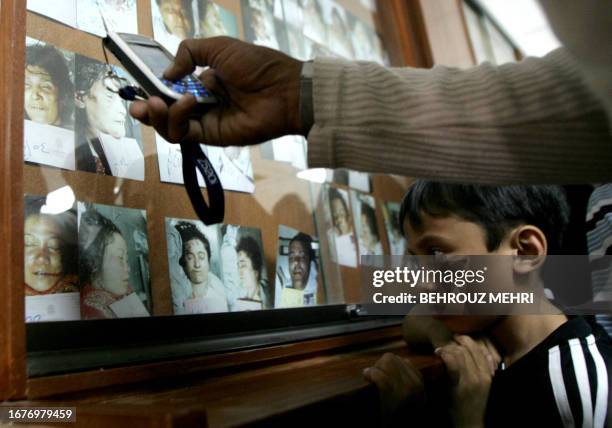 Young Malaysian boy looks at the morgue pictures of his dead mother , al-Muaysem morgue in Mina, 13 January 2006, while another pilgrim uses his...