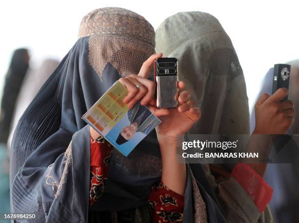 Burqa-clad Afghan women take pictures with their mobile phone at anelection gathering wait for the Afghan President Hamid Karzai in Kandahar on...