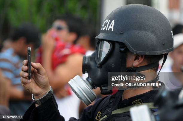 Riot police officer photographs with his mobile as protesters are arrested during a demonstration of teachers in Tegucigalpa, August 27, 2010. AFP...