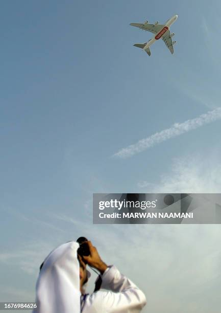 An Emirati man takes a picture of the new Emirates Airbus super jumbo, the world's largest civilian airliner, as it flies over Dubai airport on July...