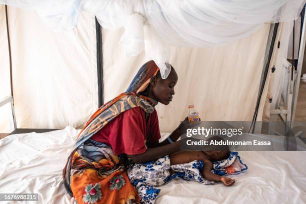 Nadifa Mohamed Adam gives water to his child who is suffering from fever and malnutrition at the malaria department tent in the Doctors Without...