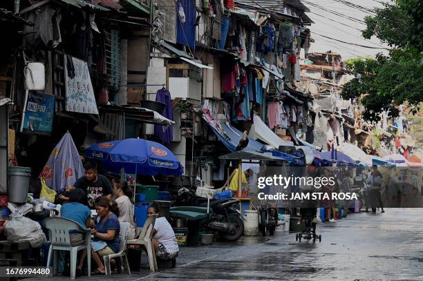 People walk past makeshift houses in Manila on September 20, 2023.