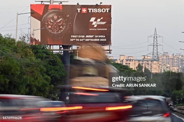 In this photograph taken on September 19 motorists ride past a billboard of India's maiden MotoGP displayed along a busy road on the outskirts of New...