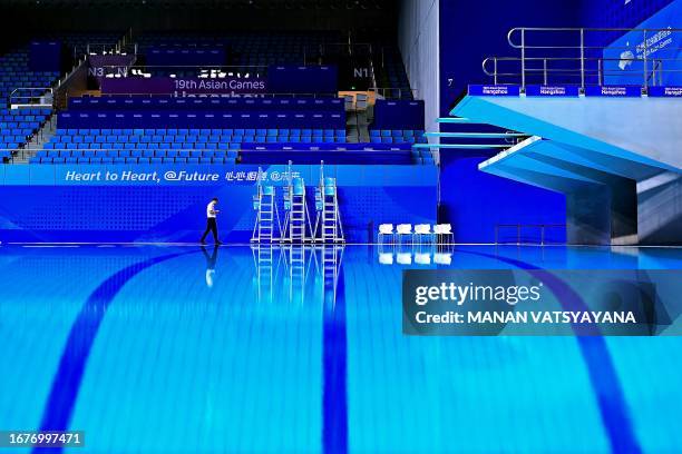 An official walks past the diving platforms ahead of the Hangzhou 2022 Asian Games at the Hangzhou Olympic Centre Aquatic Sports Arena in Hangzhou in...