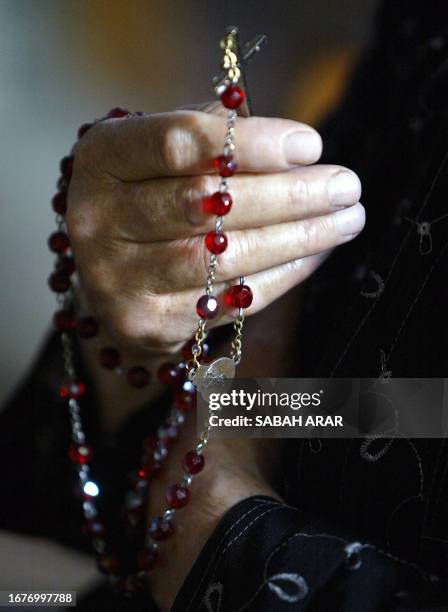 An Iraqi Christian woman holds her rosary during prays 03 April 2005 dedicated to Pope John-Paul II who passed away last night, at the St. Joseph...