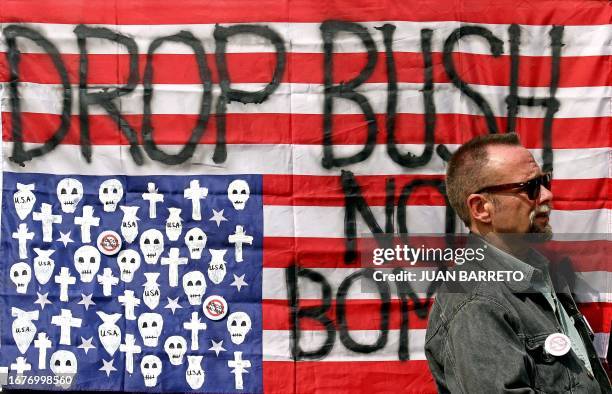 Un transeúnte camina frente a una bandera norteamericana en la que se lee "Abajo Bush, no a las bombas" cerca de las instalaciones de la embajada de...