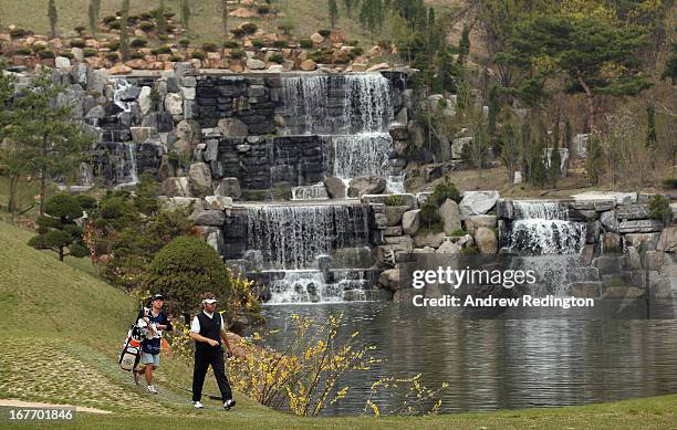 Jose Manuel Lara of Spain and his caddie walk past the waterfall on the fourth hole during the final round of the Ballantine's Championship at...