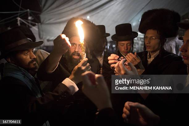 Ultra-Orthodox Jews hold a candle for the Havdala ritual during a ceremony at the grave site of Rabbi Shimon Bar Yochai in the northern Israeli...