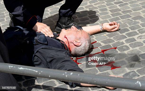 Policeman is helped after being shot by an apparently disturbed man, on April 28, 2013 in Rome, outside the palazzo Chigi, the Italian Prime minister...