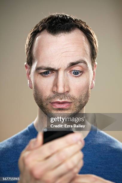 portrait of a man looking at his phone. - raised eyebrows stockfoto's en -beelden