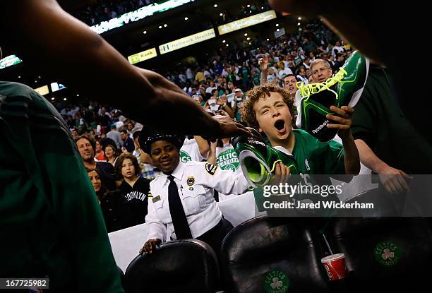 Young fan receives the game-worn pair of shoes from Jason Terry of the Boston Celtics following their overtime win against the New York Knicks during...