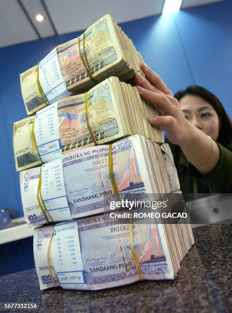 Bank teller prepares stacks of Philippine peso 28 January 2005. The local currency has rebounded in recent weeks, hitting 55.09 to a US dollar on 28...