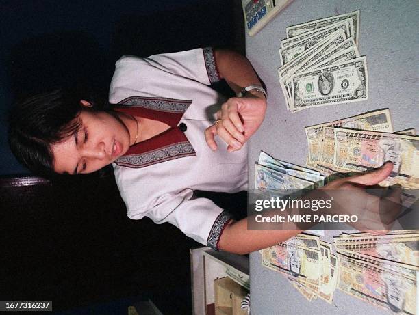Elizabeth De Leon, a bank teller sorts out US dollars and pesos for a client 21 October. The Philippine peso fell to 34.40 to the dollar. This marked...