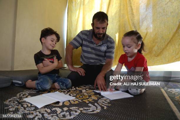 Idlib, Syria. 36-year-old Issam Al-Laham with two of his surviving children. Two of his children along with himself survived a chemical attack that...