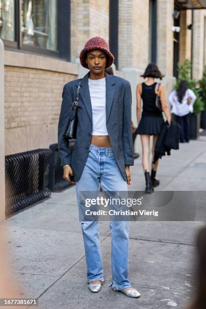 Model wears bucket hat, white cropped shirt, grey blazer, light washed denim jeans outside Brandon Maxwell on September 12, 2023 in New York City.
