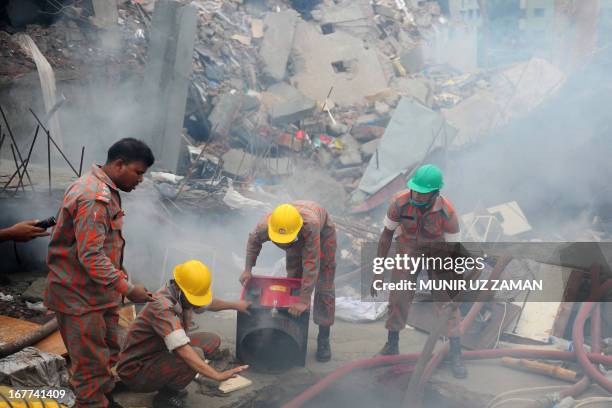 Bangladeshi fire-fighters try to control a blaze following a fire during a rescue attempt of a woman as Bangladeshi Army personel begin the second...