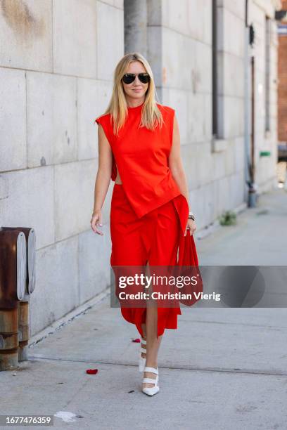 Lisa Aiken wears red sleeveless top, skirt with slit, bag outside Gabriela Hearst on September 12, 2023 in New York City.