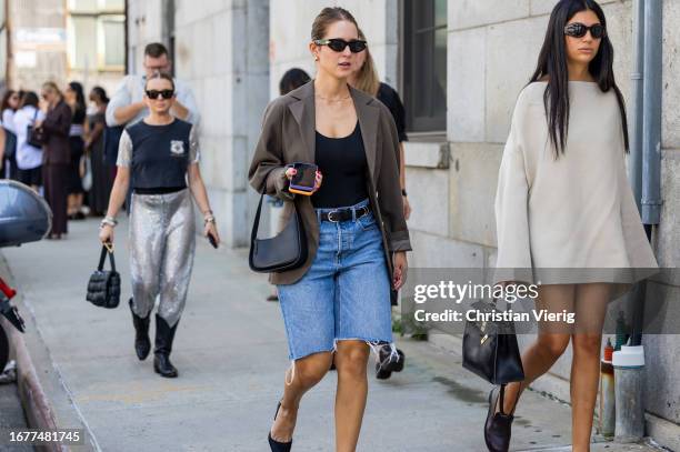 Guest wears denim shorts, brown blazer outside Gabriela Hearst on September 12, 2023 in New York City.