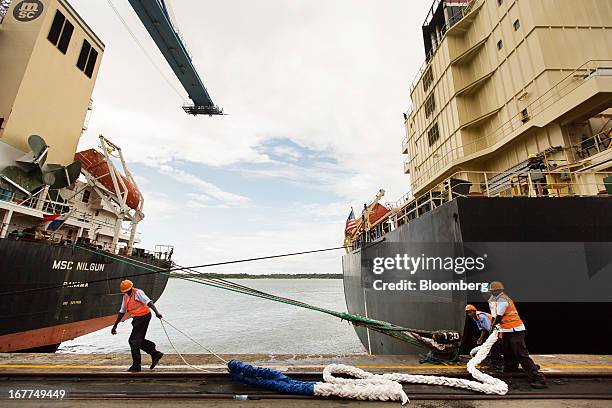 Dock workers for the Kenya Ports Authority , a state-run company, prepare to secure the Tiger container ship, right, to the quay side at Mombasa port...