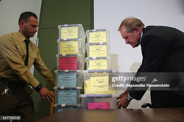 Karl Huber, President of the Oberlandgericht Muenchen court carries with a police officer the lottery boxes after a press conference following the...