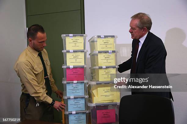 Karl Huber, President of the Oberlandgericht Muenchen court carries with a police officer the lottery boxes after a press conference following the...